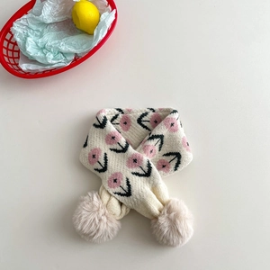 Detail of knit children scarf featuring pink flower patterns and brown pom-poms