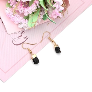 Detail of natural black raw stone earrings with gold plated hooks and dried flowers