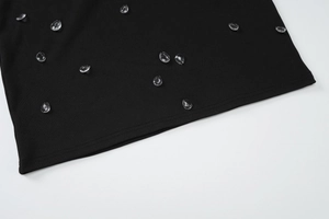 Dettaglio dell'abito in maglia a coste nere con decorazioni in cristallo a goccia