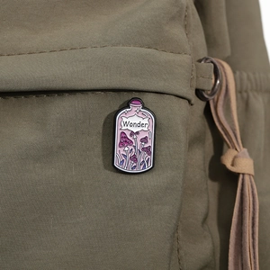 Macro shot of purple mushroom enamel pin with Wonder text on olive canvas background