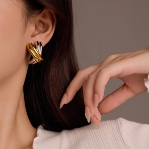 Macro detail of geometric mixed gold and silver interweaving hoops on a model's ear