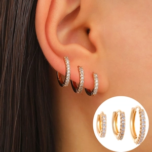 Lot de trois boucles d'oreilles créoles dorées ornées de zircons sur un mannequin
