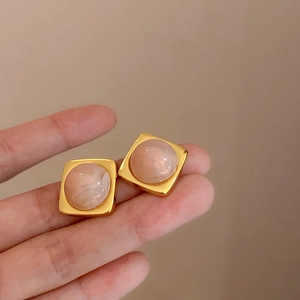 Dettaglio di orecchini quadrati dorati vintage con pietra marmorizzata rosa