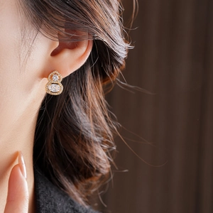 Detail view of gold plated gourd earrings with micro-set zircons worn by a model