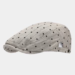 Detail of grey herringbone flat cap featuring black heart patterns and metallic buckle