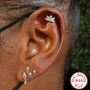 Detailed view of S925 sterling silver dog paw and lotus stud earrings on a model ear