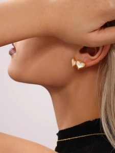 Detail shot of heart earrings with gold beaded edges and white mother of pearl inlay