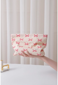 Close-up of beige cotton makeup bag with pink bow pattern and H&R BAG brand label
