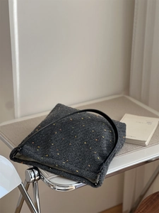 Detailed texture of thick grey tweed tote bag with colorful specks and black leather strap