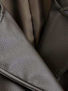 Détail du trench-coat en similicuir marron foncé montrant le revers et le grain de cuir