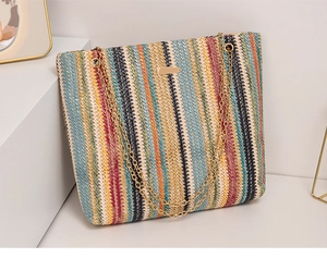 Detail of colorful striped woven bucket bag with gold chain handle and metal plaque