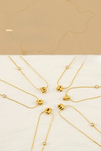 Detailed view of 3D bubble letter pendant necklace with gold finish and zircon stones