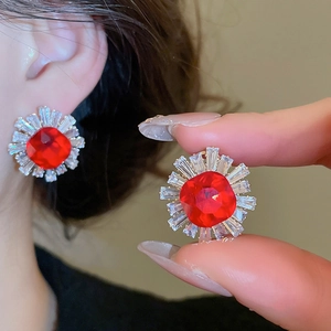 Macro detail of sunflower silver needle earrings with red gemstones and zircon crystals