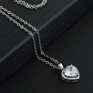 Collier cœur argenté élégant avec cristal central et halo de diamants sur fond noir
