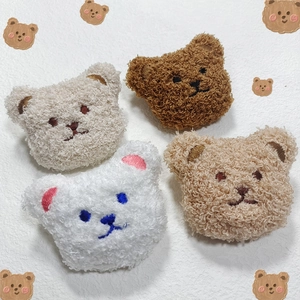 Detail of four colorful plush bear heads with embroidered expressions for DIY accessories