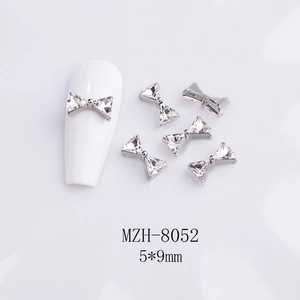 Macro shot of 5x9mm crystal bow nail charms with silver metal base on white background