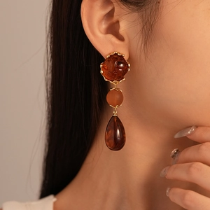 Close-up of retro amber acrylic drop earrings featuring water drop pendants and gold metal