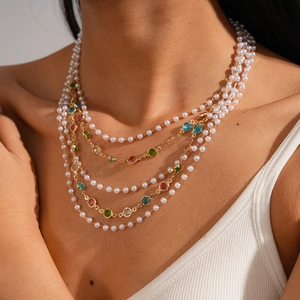 Detail of layered baroque pearl necklace with colorful gemstones and gold chains