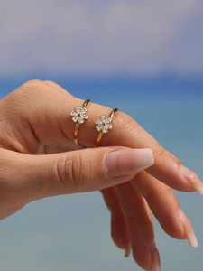 Detail of two gold flower rings with shiny white zircons worn on model's hand