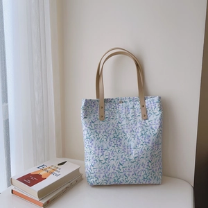 Close-up of floral cotton tote bag with premium leather handles and gold rivet details
