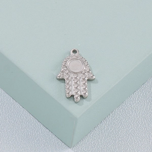 Close-up of a silver Hamsa hand pendant with dotted texture on a geometric block