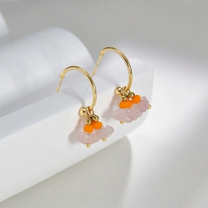 French design hoop earrings with pink crushed stones and orange beads on a white pedestal