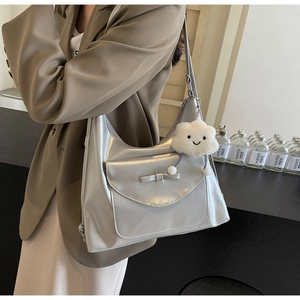 Detail of silver shoulder bag with bow and white cloud charm worn by a model