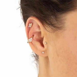 Close-up of three-piece gold geometric earrings with clear stones worn on an ear