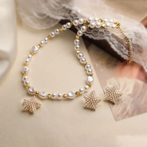 Detail view of gold star charms and white pearl necklace with matching earrings