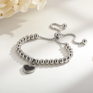 Détail du bracelet à billes argentées avec pendentif cœur noir et cordon réglable