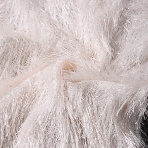 Gros plan sur un tissu peluche blanc cassé avec de longues franges et texture luxueuse