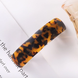 Detail shot of rectangular tortoiseshell acetate hair clip on a minimalist white card
