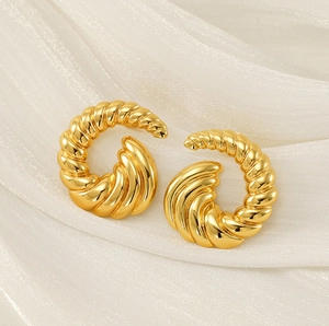 Close-up of 18k gold-plated twisted spiral stud earrings on white silk fabric background