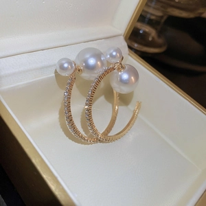 Macro shot of gold hoop earrings with sparkling rhinestones and white pearls in a box