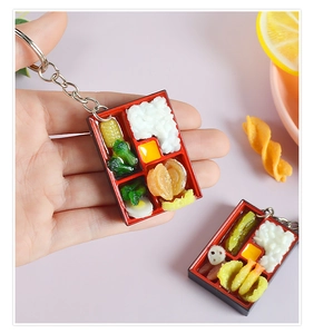 Detailed macro view of realistic miniature bento box keychain with fried shrimp and egg