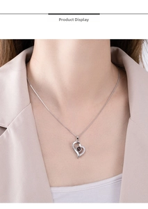 Close-up of 925 sterling silver heart projection necklace worn by a model in soft lighting