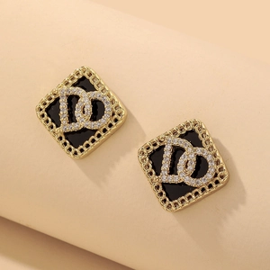 Détail de boucles d'oreilles géométriques dorées avec incrustation d'émail noir et diamants
