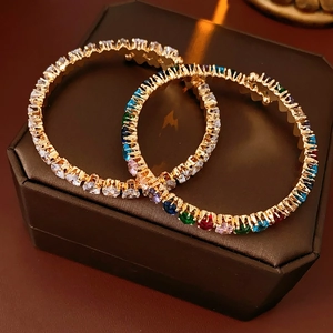 Close-up of gold-plated zircon bangles with multicolor gemstones on a jewelry box
