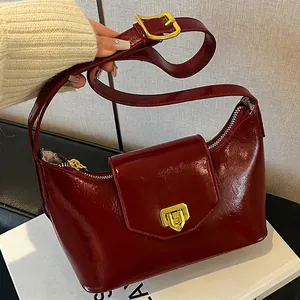 Burgundy patent leather shoulder bag with gold metal hardware and adjustable strap