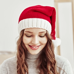 Close-up detail of a red and white knitted Christmas hat with a fluffy white pom-pom