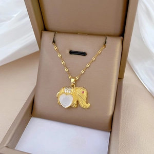 Macro detail of golden elephant necklace with heart-shaped white shell and red stone