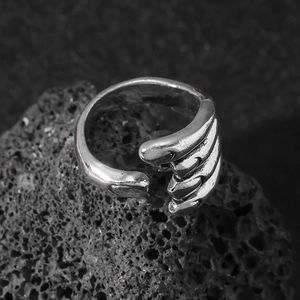 Adjustable silver claw ring with textured skeletal finger design on volcanic rock
