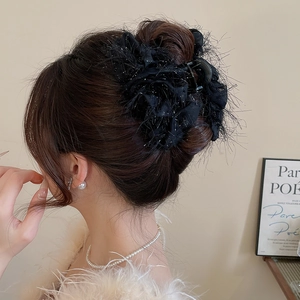 Détail d'une pince à cheveux en plumes noires à paillettes sur les cheveux
