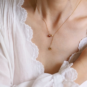 French vintage gold necklace with deep red and gold heart pendants on a female model