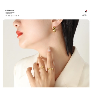 Close-up of 18K gold plated C-shaped hoop earrings with green zircon on model