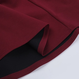 Vue macro de l'ourlet de robe bordeaux montrant une couture double et la texture du tissu