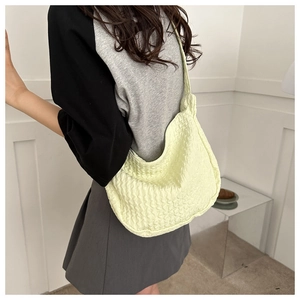 Close-up of light yellow bubble texture fabric crossbody bag on a female model