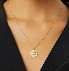 Close-up of golden solar coin pendant necklace with small crystal accents on a model