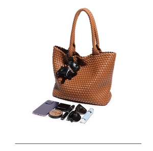 Brown woven tote bag showing spacious interior with phone, makeup and dog charm