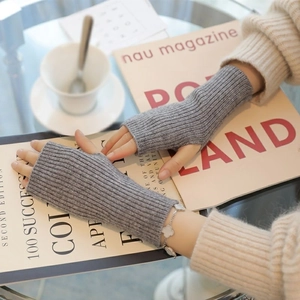 Gray knitted fingerless gloves worn by a model in a cozy, professional lifestyle setting